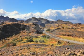 Chile. Summer in national park to Torres del Paine. The gravel road curls among picturesque hills and mountains
