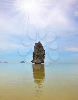 Fantastic beauty island-rock in the southern seas. The smooth sea reflects an island silhouette
