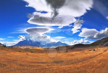 The Chile National Park Torres del Paine. Incredible shaped clouds formed by glaciers glisten in the sun. On the horizon are seen mountains with snow-capped peaks. Picture taken with a fisheye lens