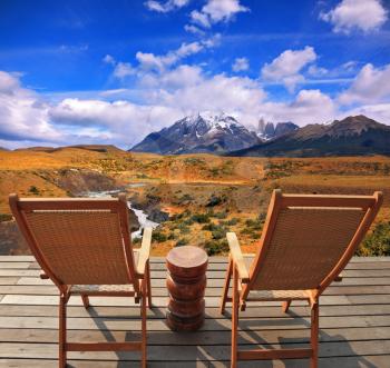 The magnificent national park Torres del Paine in Chile. Two wooden chairs - on a wooden platform.  The comfortable place to enjoy the beauty of the landscape. 