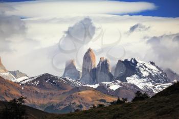 Three rocks Torres are surrounded by picturesque clouds. Fabulous harmony of the national park Torres del Paine in Chile 