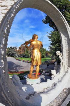 Dynamic sculptural portrait of the King of Waltz - Johann Strauss. Elegant bronze statue with violin shines in the bright summer sun