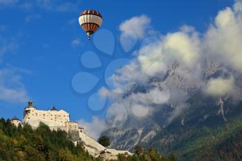 The medieval Palase Hohenwerfen. Over the castle and the mountains in the clouds flying the giant balloon