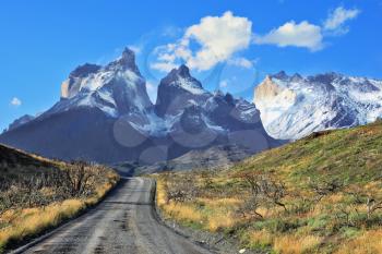 Dreamland Patagonia. Snow-covered cliffs of Los Cuernos, to them is a road of black gravel