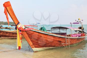 Orange Thai boat for tourists. Bow is decorated with colorful and bright silk scarves