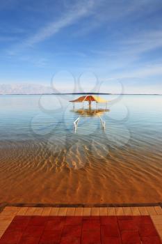 The magnificent beach on the Dead Sea. The picturesque gazebo for protection from the sun reflected in water