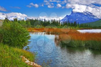 Charming shallow lake with small islands on a background of the Rocky mountains covered by a snow