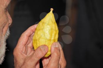 BNEY-BRAK, ISRAEL - SEPTEMBER 17, 2013:  Grand Bazaar on the eve of the Jewish holiday. The older man with gray beard picks citrus