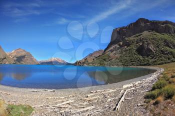 Picture taken Fisheye lens. Oval blue lake surrounded by mountains. Mountains reflected in the mirrored water 