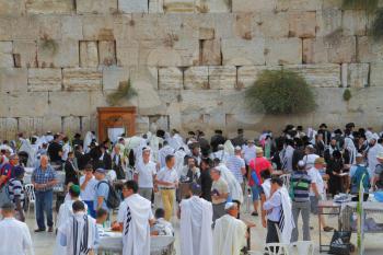 JERUSALEM, ISRAEL - SEPTEMBER 18, 2013: Sunny morning in the holiday of Sukkot. Religious Jews in white prayer shawls are going to pray at the Western Wall of the Temple