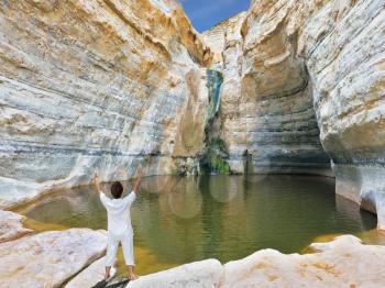 Yoga classes in the gorge Ein-Avdat, Israel. Woman in white performs asana Sun salutation