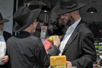 JERUSALEM, ISRAEL - SEPTEMBER 18, 2013: Traditional market before the holiday of Sukkot. The religious Jew with beard  very carefully examines ritual citrus - etrog