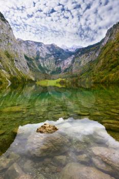 Magic reflection in German lake Koenigssee. Cloudy day on the lake. Clouds and mountains reflected in the mirrored surface of the water