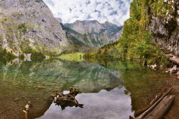 Magic reflection in German lake Koenigssee. Clouds and mountains reflected in the mirrored surface of the water. Cloudy day on the lake