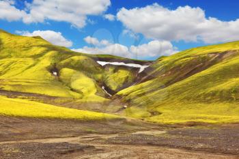  Green moss on smooth slopes and white spots snowfields in the gullies. Magnificent colorful mountains. Reserve Landmannalaugar, Iceland