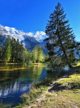 Mountain resort of Chamonix. Dreamlike beauty lake and park. In smooth water reflected snow-capped mountains