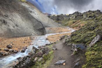 Gorge Valley Landmannalaugar. The path runs along the mossy mountainside. The gorge runs abounding stream