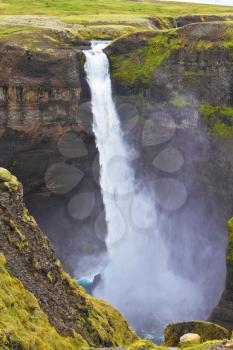 Spectacular waterfall Hayfoss in Iceland. Vertical cliff, from which the powerful waterfall flies on black stones