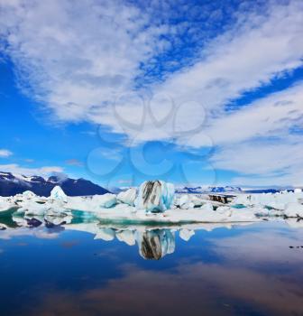  Cirrus clouds and spectacular icebergs are reflected in the ocean lagoon. Jökulsárlón Glacial Lagoon in Iceland