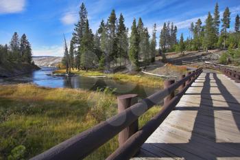 The wooden foot small bridge through a stream in wild district