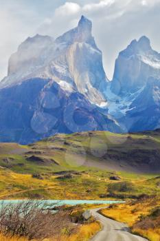 Summer day in the national park Torres del Paine, Patagonia, Chile. A dirt road leads to the cliffs of Los Kuernos