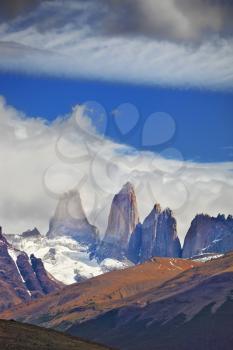  Three rocks Torres are surrounded by picturesque clouds. Fabulous harmony of the national park Torres del Paine in Chile 