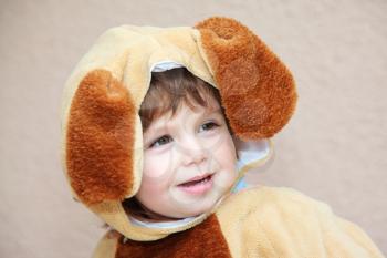 The charming little boy in a fluffy suit for a carnival with long braun ears cheerfully smiles