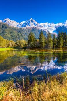 Early autumn in Chamonix, Haute-Savoie. France.  The lake reflected the snow-capped Alps and evergreen spruce
