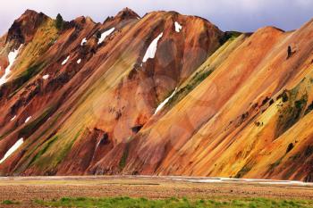 Smooth orange rhyolite mountains in Landmannalaugar nature reserve. In the hollows is last year's snow