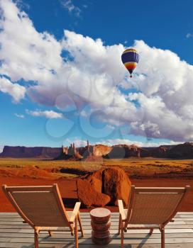 Red sandstone in the valley of the Navajo, USA. Two wooden deck chairs on the platform are to observe the Monument Valley