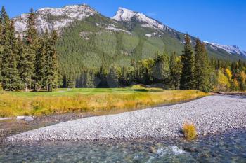 Magnificent valley in Banff National Park. Beneaped autumn stream with a pebbly bottom flows among the mountains and pine forests