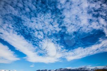 Blue sky and cirrus clouds over snowy mountains