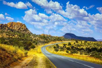Asphalt road in Namibia. Gorgeous autumn turned yellow bush and mountains in the distance