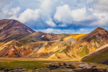  Multi-colored mountains from mineral rhyolite are lit with sun. Travel to Iceland in the July. Summer volcanic tundra
