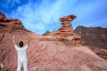 The woman - tourist in a white suit for yoga delighted raised her hands. Warm January day. The mountains of pink sandstone