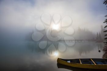 Emerald Lake in Yoho National Park. The sun peeps through the mist. Fishing boats moored on the shore
