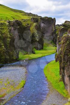 Canyon Fjadrargljufur and cold fast river with a pebble bottom. Iceland in the summer