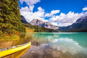 Sunny day in autumn Yoho National Park. In shallow water, the boat is moored. The concept of eco-tourism and active tourism. The mountain Emerald lake  