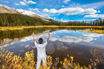 Mature interesting woman in a white suit for yoga. Beautiful nature of the Rocky Mountains of Canada