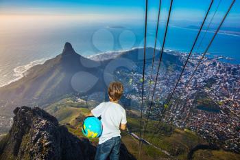 Travel to Africa. Panorama Cape Town, photographed from  cableway cabin. The concept of active tourism and recreation. The boy with the globe in hands standing on top of Table Mountain