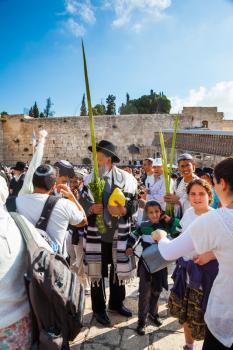 JERUSALEM, ISRAEL - OCTOBER 12, 2014:  Morning autumn Sukkot. The area in front of Western Wall of Temple filled with people. The Jews of ritual clothes - tallit hold four plants on Sukkot