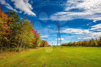 Red and green autumn foliage. Electricity transmission air-line support. Shining sunny day in French Canada
