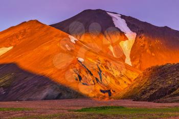 Morning dawn  National Park Landmannalaugar, Iceland. Mountains and glaciers covered with warm pink and orange sunlight