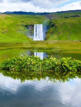  Abounding waterfall Skogafoss reflected in a small pond near the road. An incredible reflection