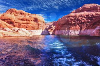  Walk on the tourist boat. Foam boat trail crosses the emerald waters. Red sandstone hills surround the lake. Lake Powell on the Colorado River