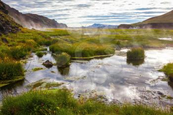 Hot steam over the source of the thermal waters.  White nights in Iceland. Sunrise Park Landmannalaugar