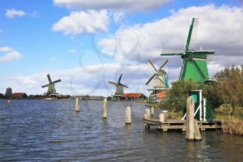The village - an ethnographic museum in Holland. Four windmills and berthing columns on the bank of the channel