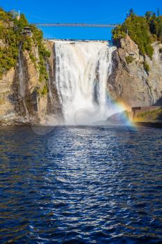 The magnificent rainbow plays in falls splashes. The blue lake and powerful waterfall Montmorency in Montmorency Falls Park, in Quebec. The concept of active and cultural tourism