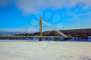 Snowy winter in the Arctic, Rovaniemi. Magnificent String Bridge through the frozen river of Kemijoki