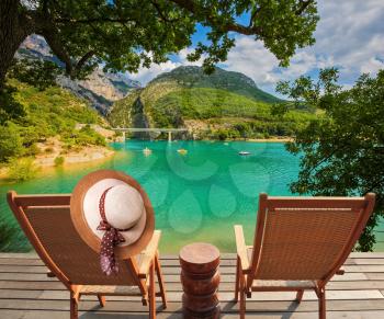  Travel to Provence. Two wooden chairs and straw hat on the platform at lake Verdon